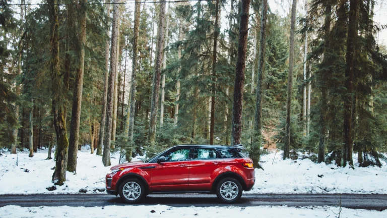 Red SUV parked on a snowy road in a winter forest