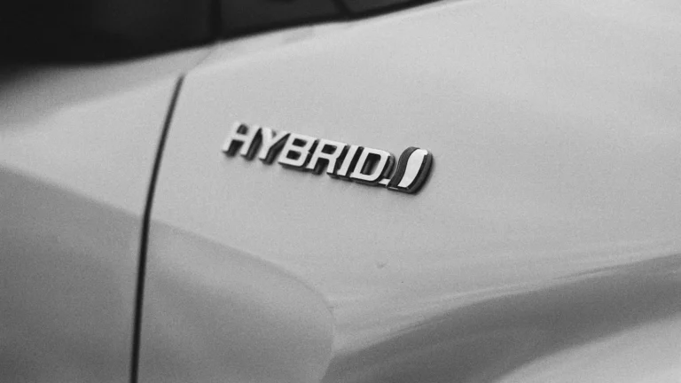 Close-up of a hybrid badge on a silver car