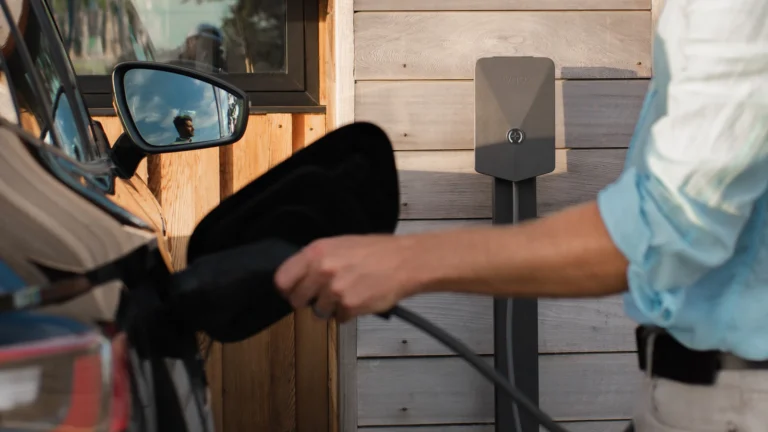 Driver plugging an electric car into a wall-mounted home charger